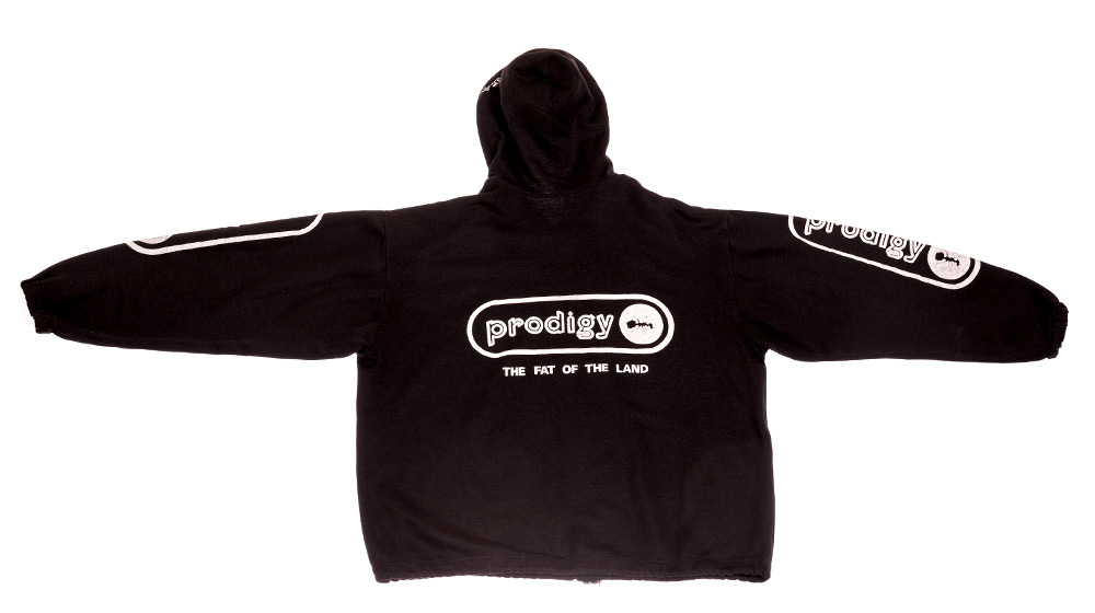 Schwarzer Kapuzenpulli mit weißem „prodigy – THE FAT OF THE LAND“-Logo auf dem Rücken und kleinen Prodigy-Logos an den Ärmeln.